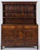 An 18th Century oak dresser:, the shelved superstructure with a moulded cornice,
