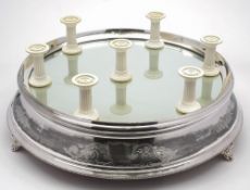 An Edwardian electro-plated wedding cake stand: of circular outline with mirror plate to the top,
