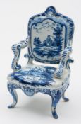 A Dutch delft model of an open armchair: with padded back and seat, scroll arms and cabriole legs,