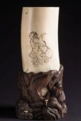A Japanese carved ivory tusk vase: decorated with a courtesan and an attendant holding a lamp,