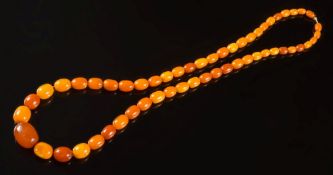 An amber coloured bead, single string necklace: with beads graduated from 9mm long to 20.5mm long.