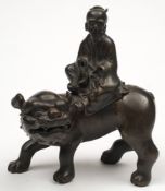 A Japanese bronze figure group of a deity seated on the back of a lion: 21cm.