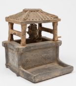 A Chinese pottery model of a well: with ridged roof, the walls embossed with designs of figures,