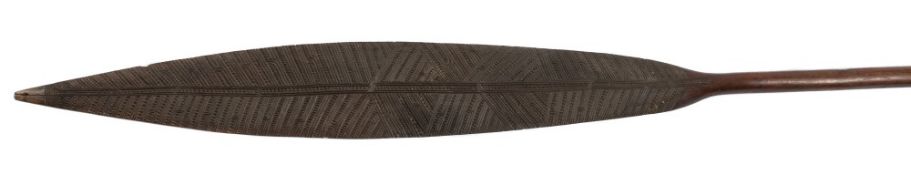 A Maori war paddle: the shaped blade with carved geometric decoration to one side,