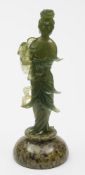A Chinese carved green hardstone figure of a female Immortal: holding a fruiting peach branch and
