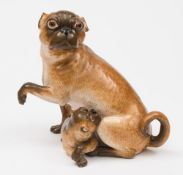 A Continental porcelain pug group: modelled with seated a seated pug, head turned,