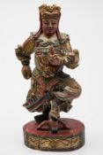 An Oriental carved and painted wood figure of a warrior: wearing ornately decorated armour and