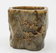 A Chinese carved hardstone bitong: carved in low relief with prunus blossom decoration, 12cm. high.