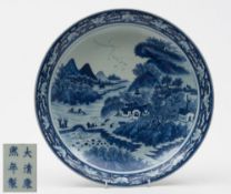 A Chinese porcelain shallow dish: of circular form painted in blue with an extensive landscape
