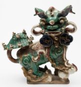A large Chinese glazed stoneware figure of a Buddhist lion dog: decorated in green,