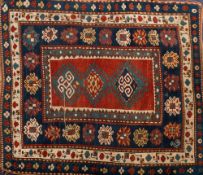 A Kazak rug:, the red oblong central panel with triple hooked geometric medallions,