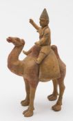 A Chinese painted pottery figure of a Bactrian camel and rider: the camel with long saddle cloth