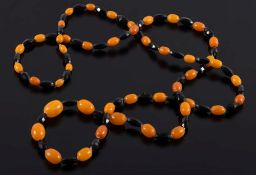 A long graduated amber coloured bead and faceted jet bead,