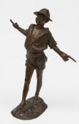 A Continental bronze figure of a boy: wearing a straw hat with stick behind his back,