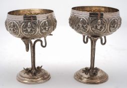 A pair of Indian silver goblets: the circular bowl decorated with roundels depicting dancers,