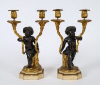 A pair of 19th century bronze and ormolu twin branch candelabra: with foliate decorated nozzles and