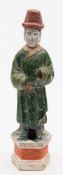 A Chinese pottery figure of a Court attendant with detachable head: wearing a high red hat and