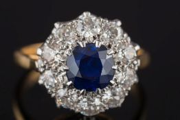 A sapphire and diamond circular cluster ring: with central round sapphire approximately 1.