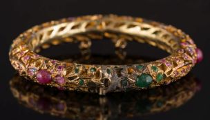 An Indian style emerald and ruby mounted bangle: with cabochon and circular-cut emeralds and rubies,