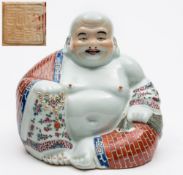 A Chinese porcelain figure of a seated Buddha: in typical posture wearing a brick decorated robe