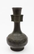 A Chinese bronze vase of archaic design: of ovoid form with two tubular handles to the slender neck,