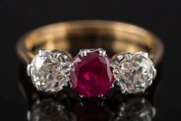 An 18ct gold, ruby and diamond three-stone ring: with central round ruby approximately 0.