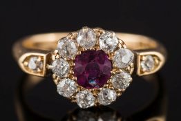An Edwardian ruby and diamond circular cluster ring: the central round ruby approximately 0.
