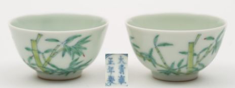 A pair of Chinese porcelain wine cups: each of circular form, the exterior enamelled with bamboo,