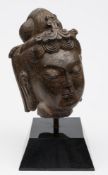 A Chinese carved stone head of Guanyin: with smiling face and downcast eyes,