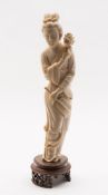 A Japanese ivory okimono of a courtesan: holding a fan in one hand and a lotus flower in the other,