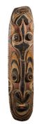A Papua New Guinea carved and painted wood shield: carved and painted with stylised masks,