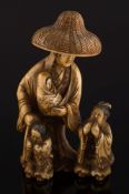 A late 19th century Japanese carved ivory okimono: of a woman wearing a domed wicker hat with three