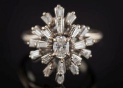 A diamond mounted cluster ring: with central oval diamond within a star-burst surround of tapering