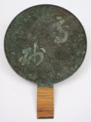 A Japanese bronze hand mirror: one side polished, the other cast with two large characters,