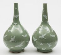 A pair of Chinese celadon glazed bottle vases: each decorated in white enamel with butterflies,