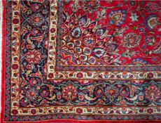 An Indo Persian carpet of Kashan design:, the crimson field with a central flowerhead medallion,