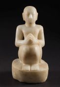 An Indo/Burmese carved white marble figure: of a seated praying monk, on raised oval base,