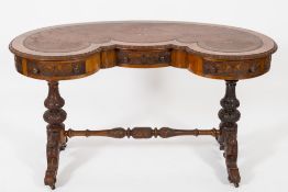 A Victorian carved walnut writing table: of kidney-shaped outline,