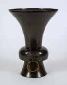A Chinese bronze vase: of trumpet shaped outline, the knopped stem with dragon mask ring handles,