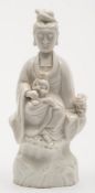 A Chinese Dehua blanc de chine porcelain figure of Guanyin: robed and in seated posture on a rocky