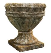 A reconstituted stone circular garden urn:, with reeded body on square base,
