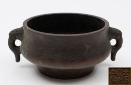 A Chinese bronze censer: of ogee form with pierced mythical beast head handles,