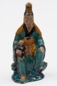 A Chinese sancai glazed seated figure of Guanyin: wearing flowing robes and with a child on one