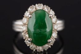 A jade and diamond oval cluster ring: the oval jade within a surround of single-cut diamonds,