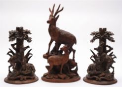 A pair of Black Forrest carved linden wood stands: decorated with stags and does below trees,