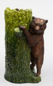 A Bretby pottery stick stand: modelled as a bear cub with inset glass eyes climbing a tree trunk,