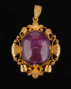 An oval cabochon ruby single-stone pendant: within scroll pierced design frame,