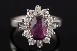 An 18ct white gold, ruby and diamond oval cluster ring: the central 'native-cut' oval ruby,