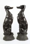 A pair of 20th century bronze seated whippets: raised on octagonal plinth bases, 80cm. high.