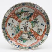 A Chinese famille verte dish: painted with a central vase of flowers surrounded by lappet
